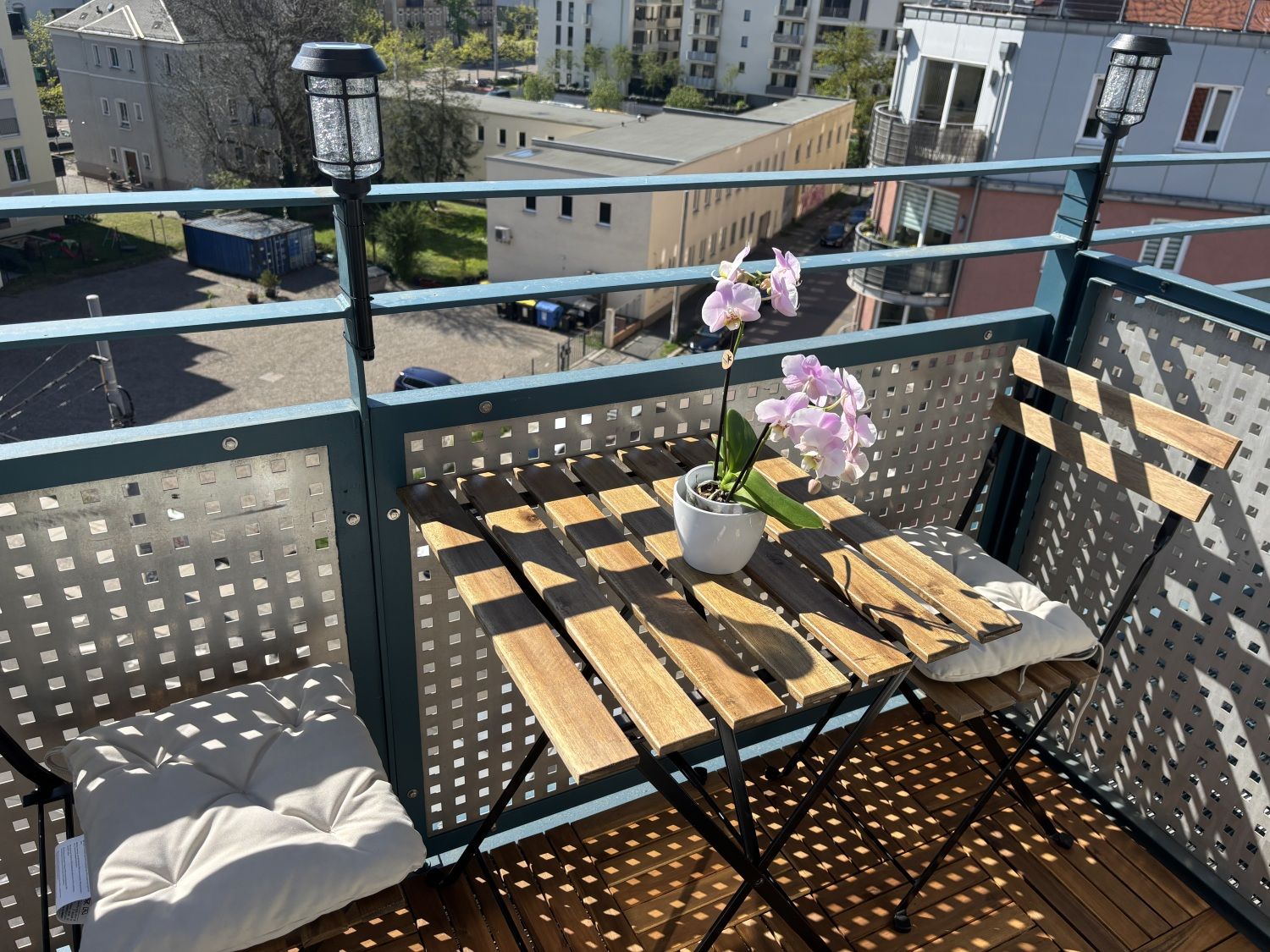 Balkon mit Tisch und zwei Stühlen, dahinter der Blick über Dresden