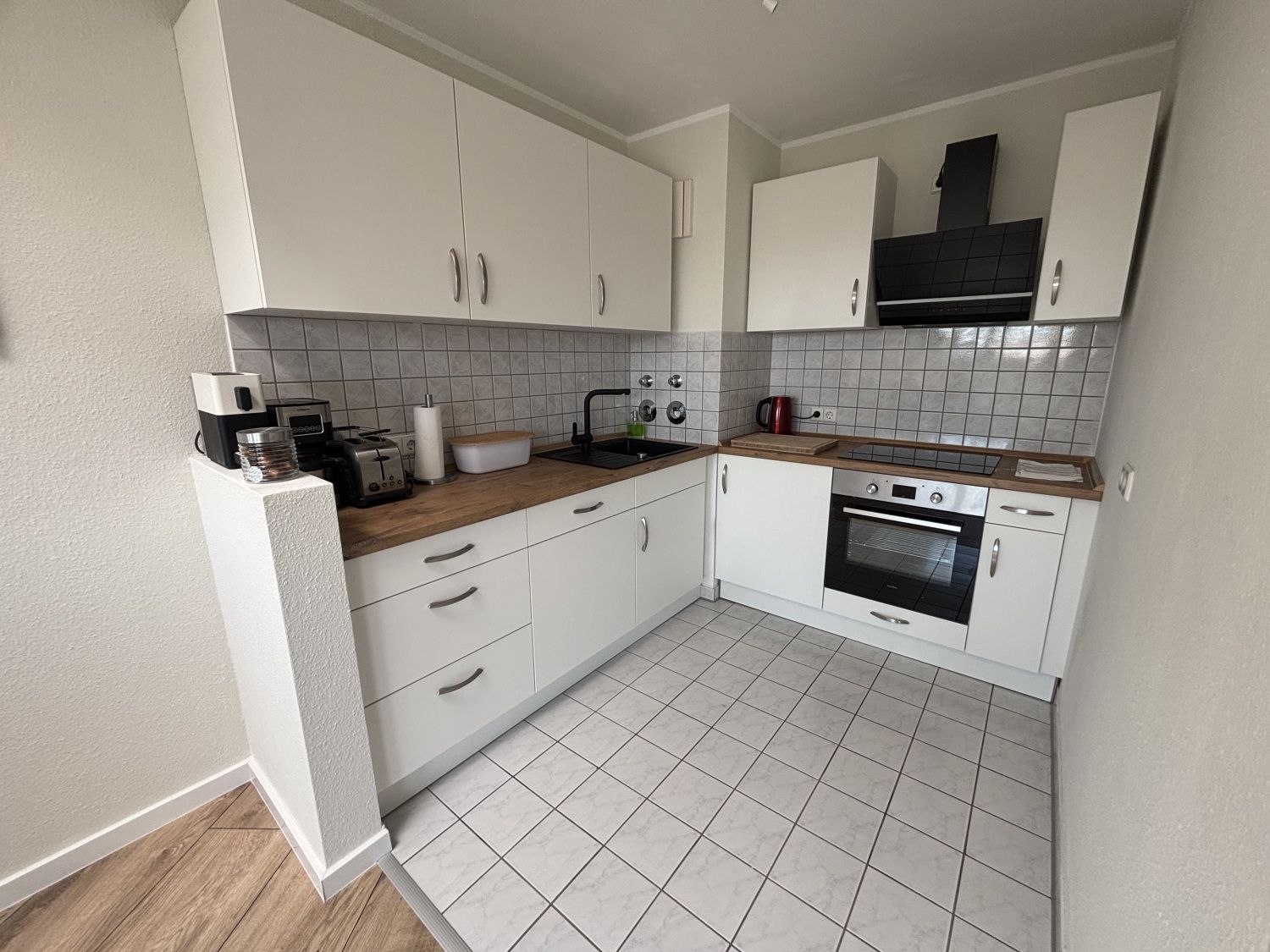 Küche mit Backofen, Dunstabzug und heller Arbeitsplatte
