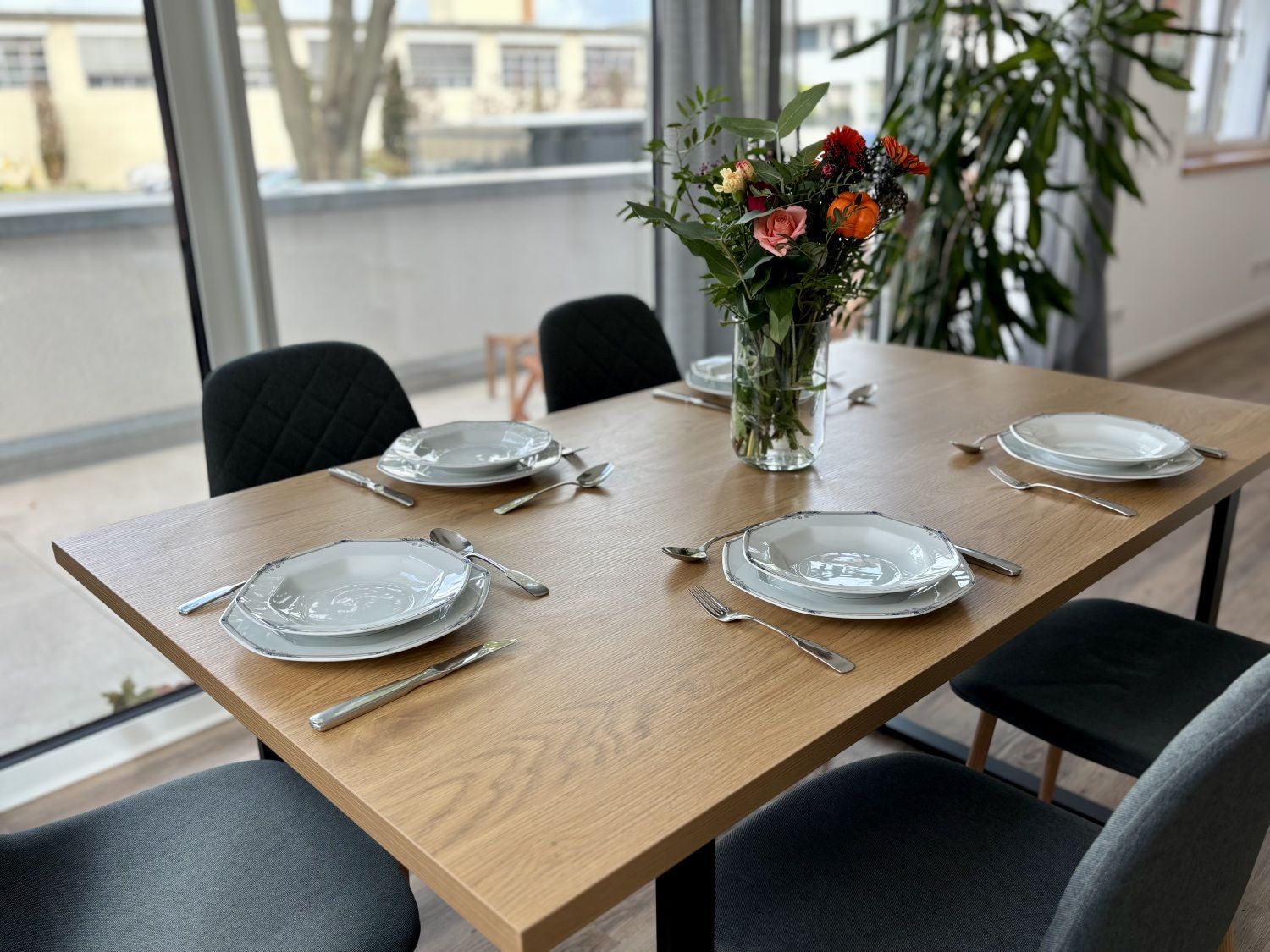 Esstisch für sechs Personen am Fenster, gedeckt mit Blumenstrauß