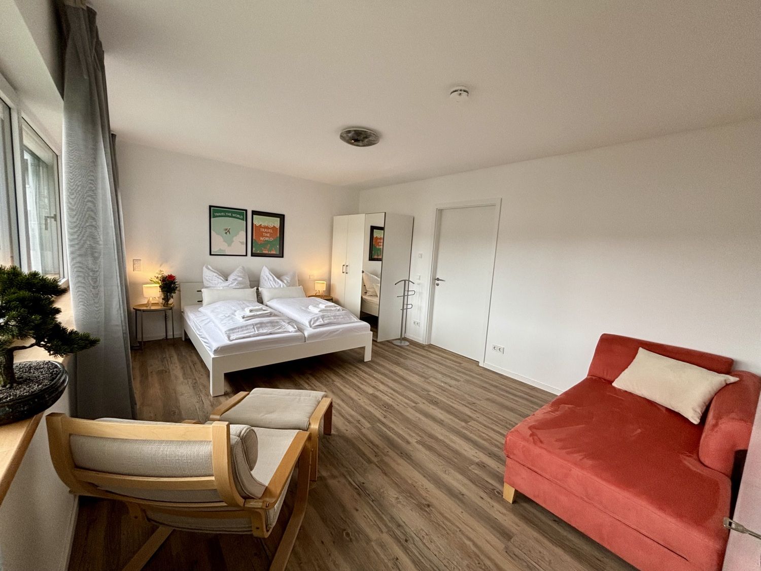 Schlafzimmer mit Doppelbett, Sessel und roter Récamiere